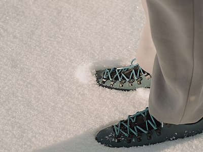 Zwei Paar Füße in Wanderschuhen stehen im frischen, knöchelhohen Schnee